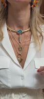 Mode wearing gold chain necklaces with charms and pendants layered on her necklace in a white blouse