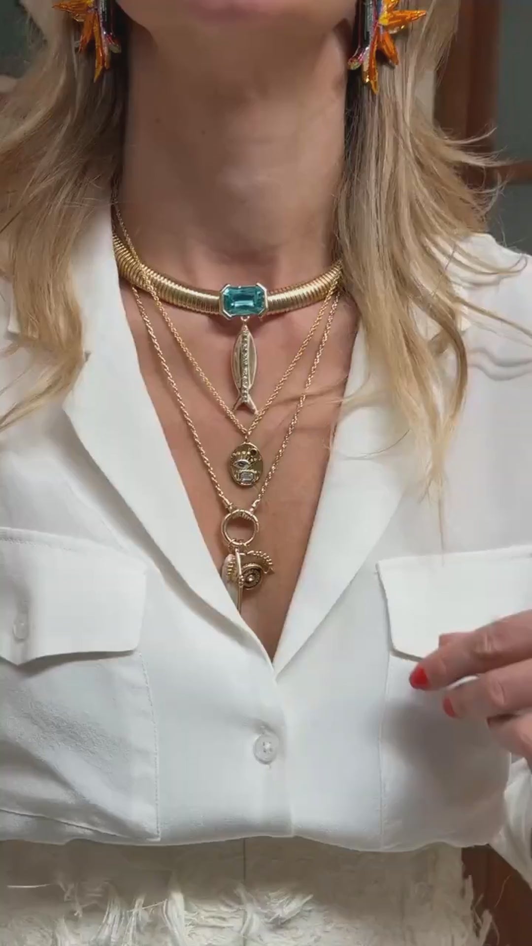 Mode wearing gold chain necklaces with charms and pendants layered on her necklace in a white blouse