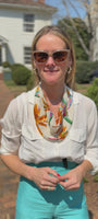 Video of model wearing colorful beaded scarf necklace outside a white house in a white top and blue pants