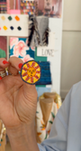 Video of model hold embroidered earring stud with a sun face on the against a mood board background