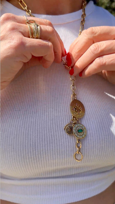 Model wearing white tank top shirt explaining gold chain necklace outside of a house