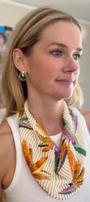 Model wearing green snail shaped earrings with colorful beaded scarf necklace