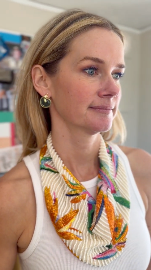 Model wearing green snail shaped earrings with colorful beaded scarf necklace