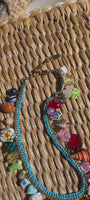 Turquoise necklace with shells and semi precious stones laid down on a wicker table