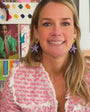 Model wearing pink woven jacket while explaining the Marea Earrings, a purple and orange embroidered drop earring