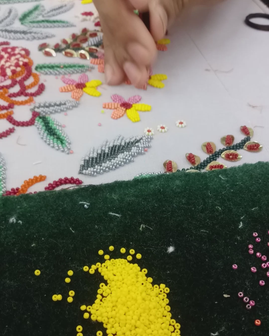 Video showing a person hand beading and hand embroidering a scarf necklace and embroidered pieces of jewelry