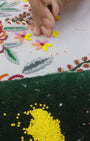 Video showing a person hand beading and hand embroidering a scarf necklace and embroidered pieces of jewelry