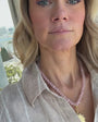 Model wearing a pink beaded stone necklace with a carved pink stone pendant
