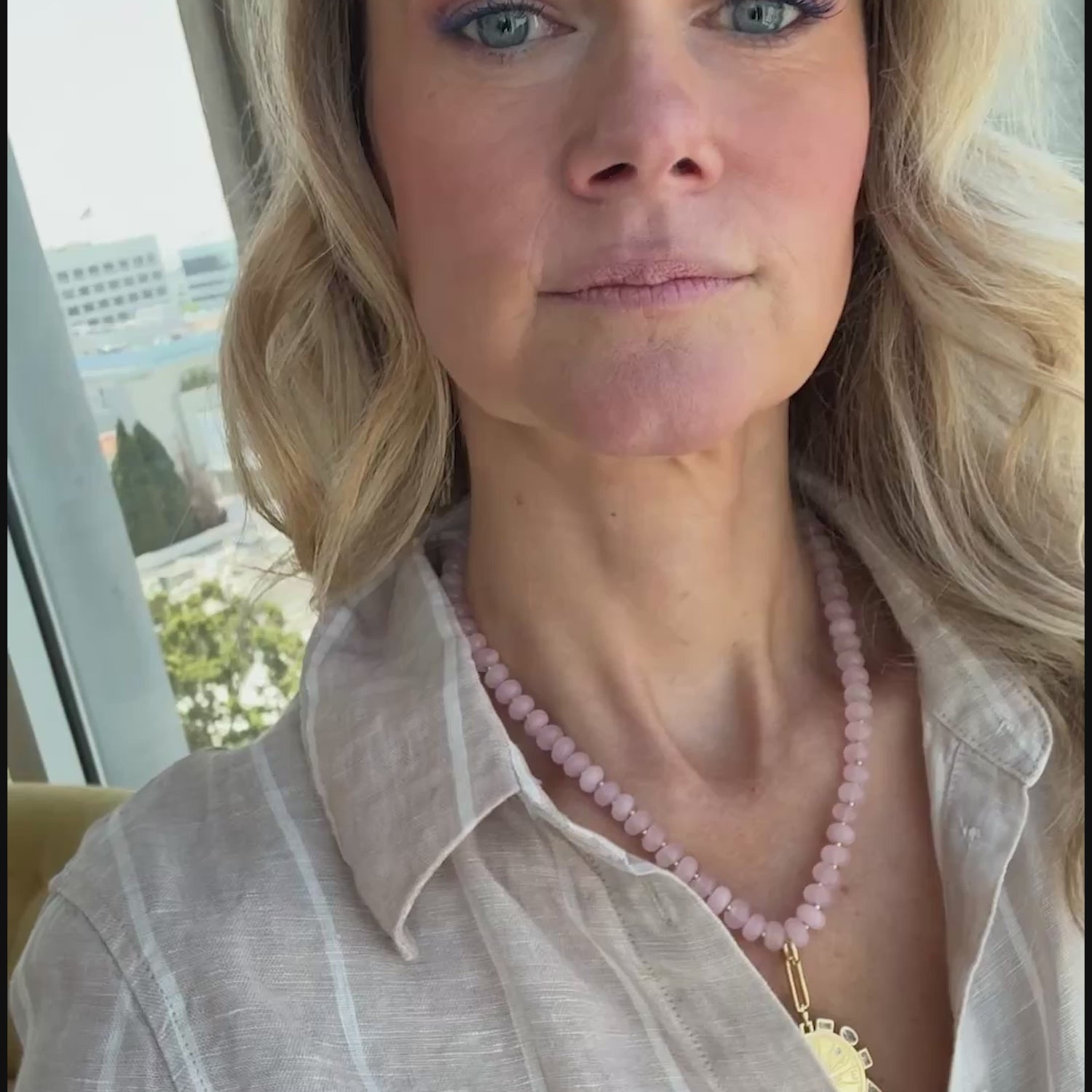 Model wearing a pink beaded stone necklace with a carved pink stone pendant