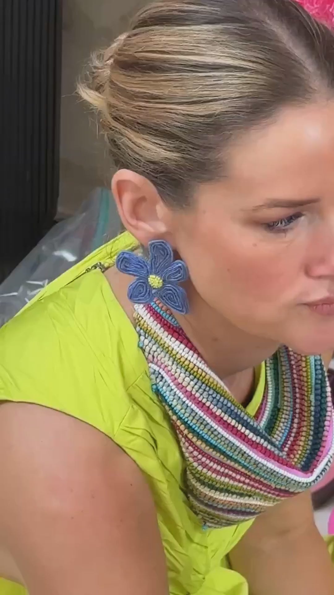 Model wearing blue floral shaped earring made with beads and threads while wearing a yellow dress and colorful scarf necklace