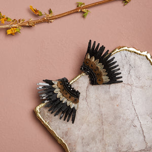 Black Sequin Wing Stud Earrings with Bronze and Silver Sequins and Beads Staged on Stone with Pink Background