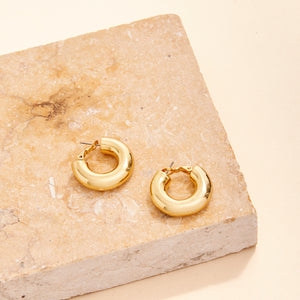 Gold Hoop Earrings Staged on Stone with Cream Background