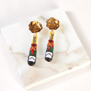 Gold, Red, Green, Black, and White Beaded Champagne Bottle Drop Earrings Staged on Stone with Cream Background