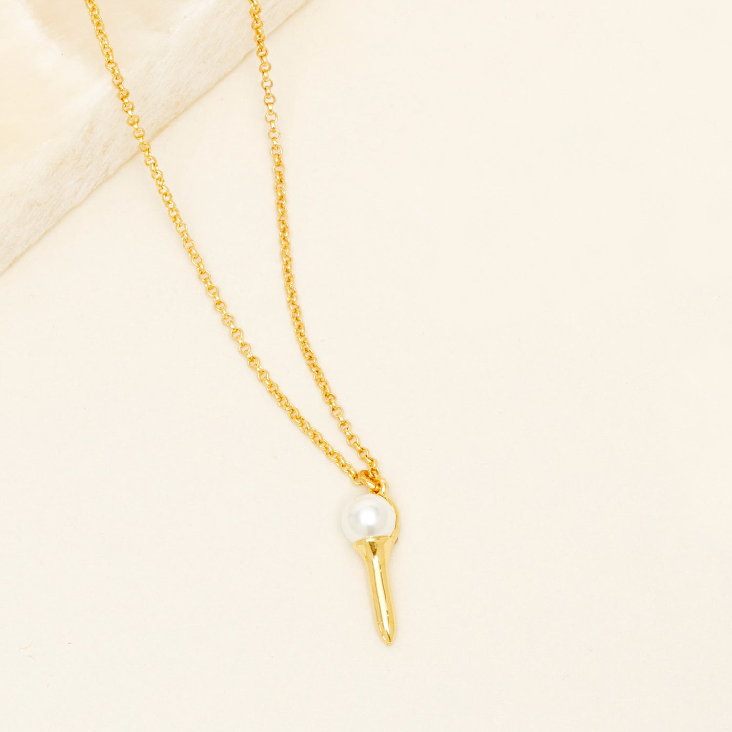 Gold and Pearl Golf Tee Necklace on Tan Background
